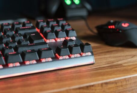 Smart Appliances - Contemporary personal computer monitors with programming codes placed on desk with backlit keyboard and mouse in light room