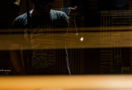 Voice Control - Through glass of musician in headphones recording song into microphone in modern music studio