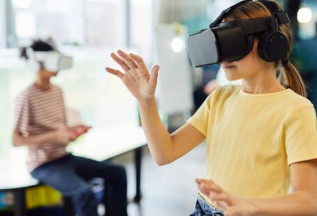 Wearable Tech - Young female in VR glasses standing in light room and testing new device