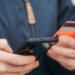 Mobile Payment Apps - Anonymous guy with plastic card making online payment using smartphone on street