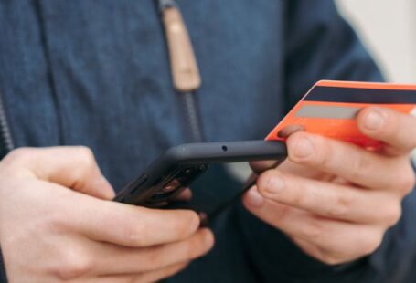 Mobile Payment Apps - Anonymous guy with plastic card making online payment using smartphone on street