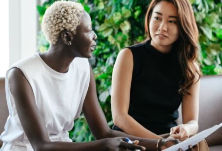 Smart Contracts - Diverse women talking about job while discussing contract and looking at each other in conference hall