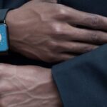 Wearable Devices - Anonymous person adjusting suit of unrecognizable African American gentleman in elegant outfit with modern smart watch